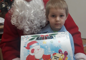 Na zdjęciu widać Mikołaja oraz chłopca z otrzymanym prezentem